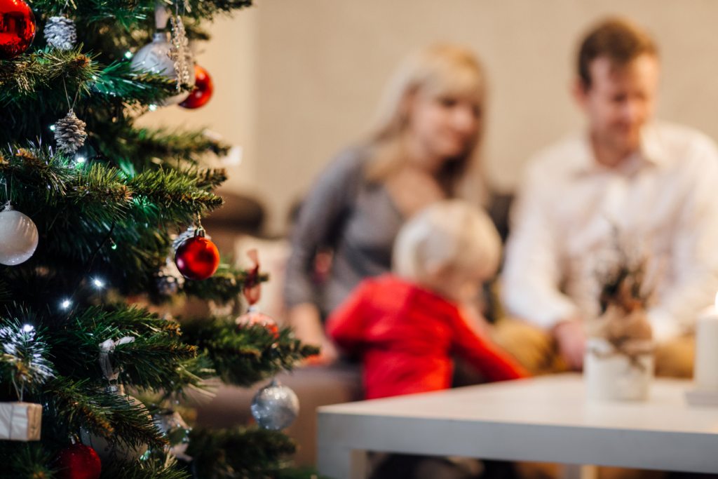 une famille de trois personnes à coté du sapin de noel