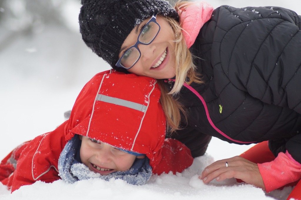 une maman et son enfant couchés sur la neige 