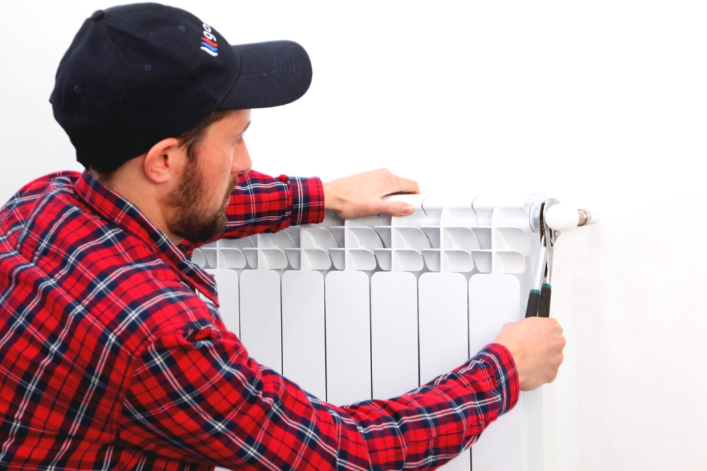 chauffagiste qui fait la purge d'un radiateur